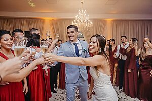 Bride and groom celebrating with guests at a wedding reception with champagne toasts and dancing.