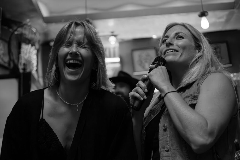 A grey scale image of two women singing into a microphone