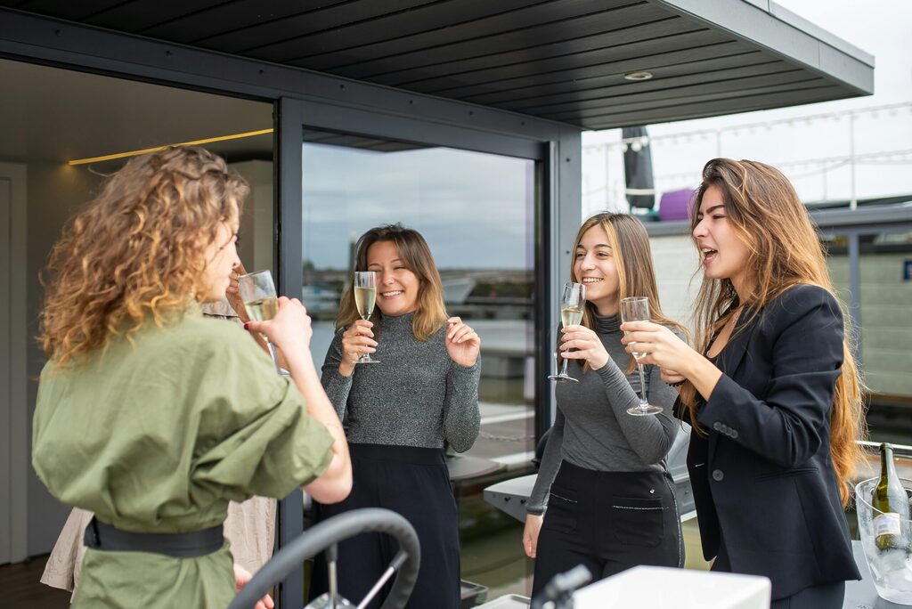 4 women drinking champagne, celebrating a corporate event on a balcony outside the office