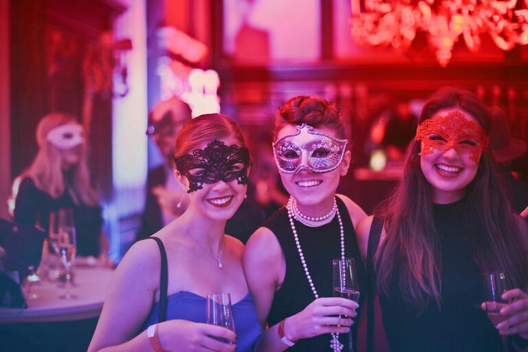women at a party with masks on having a good time